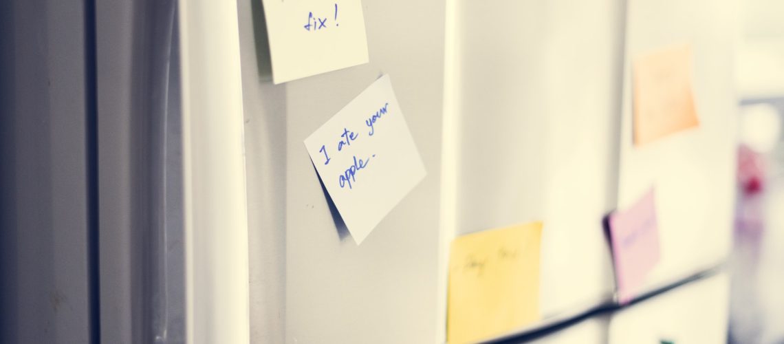 Closeup of reminder paper note on fridge door