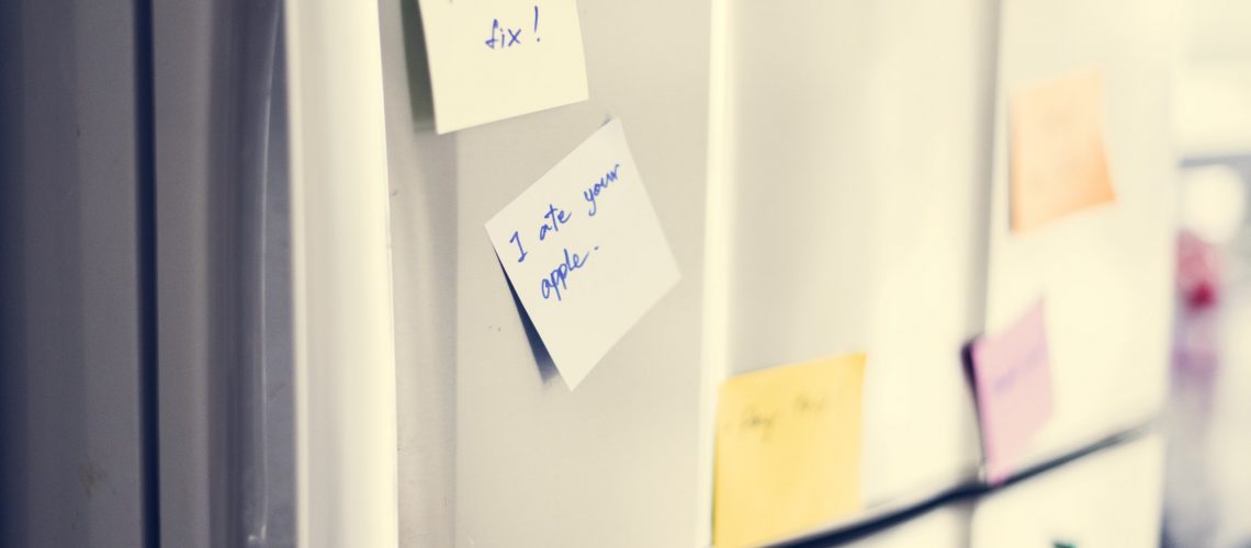 Closeup of reminder paper note on fridge door